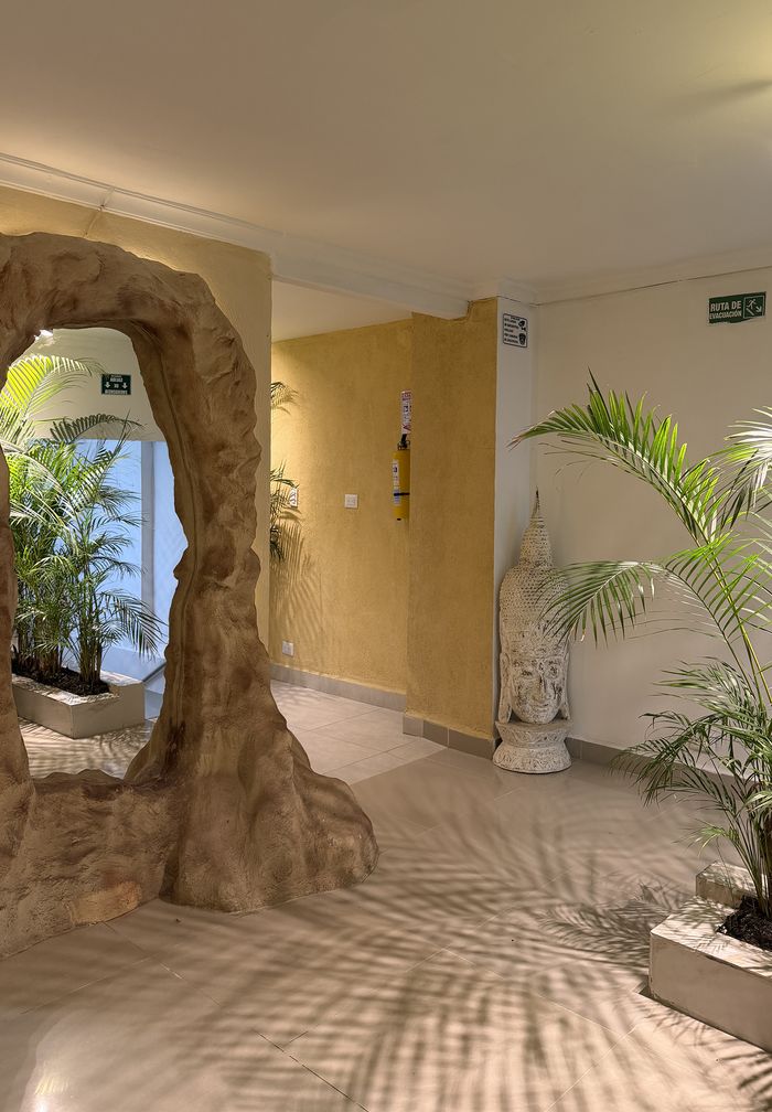 Arco de piedra entre palmas y escultura de buda en la entrada