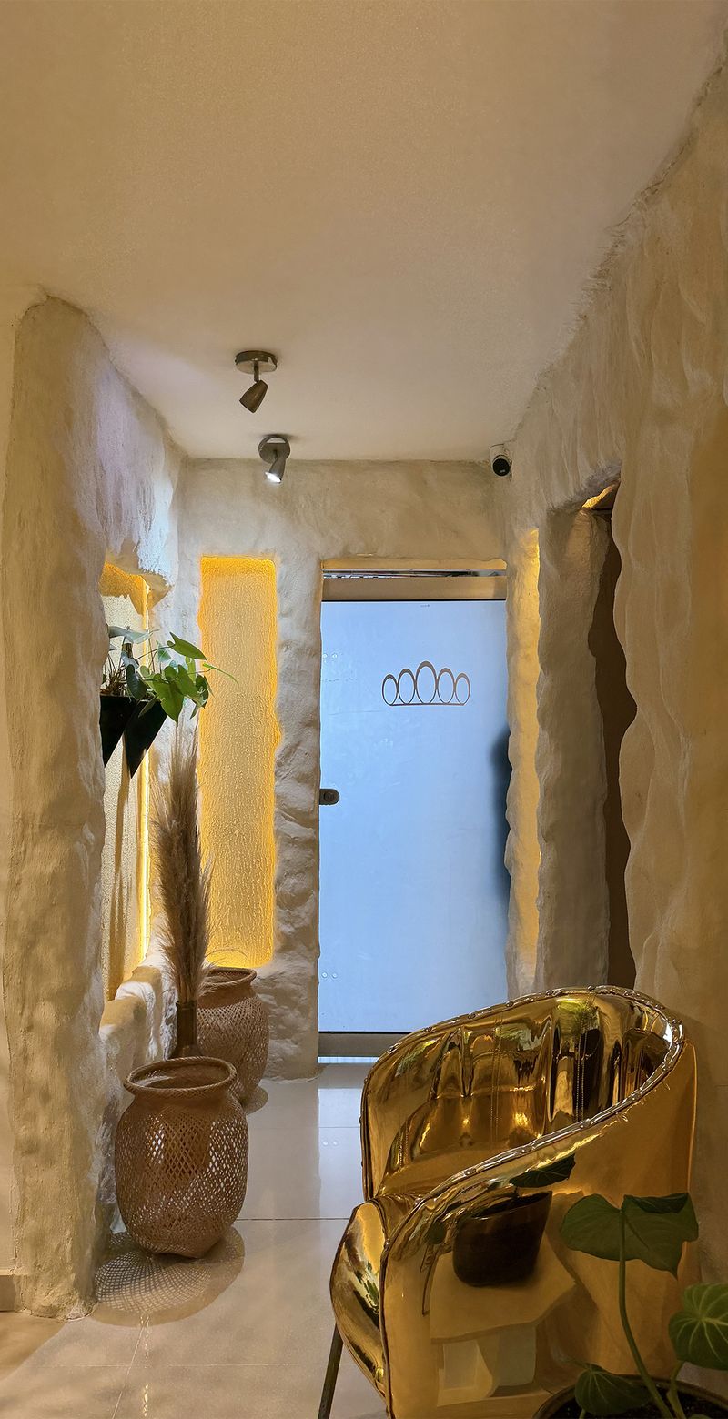 Pasillo de piedra iluminado con silla dorada y plantas